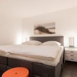 Bedroom with bed, nightstand, and wall art.
