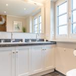 Bathroom with two sinks, mirror cabinet, and window