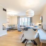 Dining area with table, chairs, and windows. Living area with sofa and floor heating.