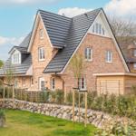 Two-story brick house with dark roof and landscaped garden