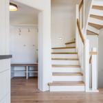 Haus mit Holztreppe, Garderobe und Schrank. Holzboden und weiße Wände.