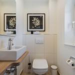 Badezimmer mit Waschbecken, Toilette und Fenster.