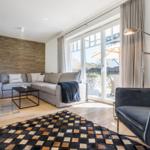 Wohnzimmer mit Sofa, Kamin und Terrasse