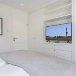 Schlafzimmer mit Bett, TV und weißen Schränken.