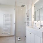 Badezimmer mit Dusche, Waschbecken und Heizkörper.