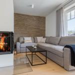 Wohnzimmer mit Sofa, Kamin und großem Fenster