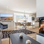 Wohn- und Essbereich mit Kamin, TV und Essplatz. Holzboden und modernes Mobiliar.
