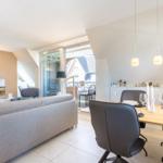 Living and dining area with sofa, TV, and table with chairs.