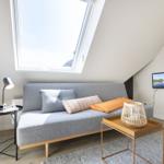 Attic room with sofa bed, skylight, and wall-mounted TV.