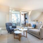 Living and dining area with sofa, armchair, and TV. Terrace with view of house.