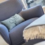A blue armchair with cushion and blanket