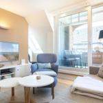 Living room with TV, seating, and view to balcony.