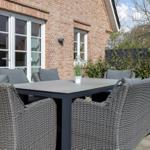 Terrasse mit Sitzgruppe vor Backsteinhaus mit Fenstern.