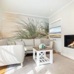 Wohnzimmer mit Sofa, Kamin und Wandbild von Strandgras.
