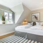 Schlafzimmer mit Doppelbett, Fenster und Wandbild.