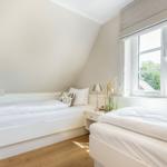Zwei Betten in einem Schlafzimmer mit Fenster und Fernseher.