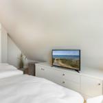 Schlafzimmer mit Dachschrägen, Bett, TV und Schrank.