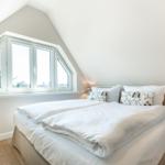 Doppelbett mit weißen Bettwäsche und Fenster mit Blick.