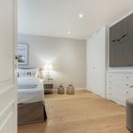 Schlafzimmer mit Bett, Nachttisch, Kleiderschrank und Wandbild.