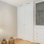 Schlafzimmer mit weißem Schrank, Kommode und Wandbild mit Vogel.