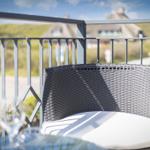 Terrace with chair and table, view of green landscape and house in the background.