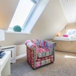 Attic room with bed, armchair, and skylight