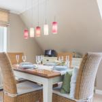 Dining room with table, chairs, and pendant lights under sloped ceiling