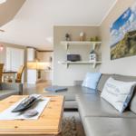 Wohnzimmer mit Sofa, Couchtisch und Küchenbereich im Hintergrund.