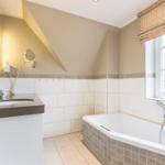 Badezimmer mit Badewanne, Waschbecken und Fenster