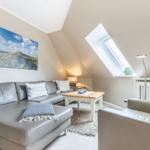 Wohnzimmer mit Sofa, Couchtisch und Dachfenster. Wandbild und Beleuchtung sichtbar.