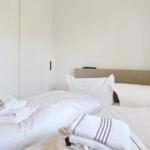 Bedroom with bed, pillows, and folded towels. A wardrobe stands behind the bed.