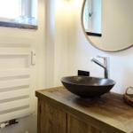 Bathroom with wooden vanity, round mirror, and heater.