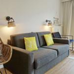 Gray sofa with yellow cushions, rattan chair, and garden view through window.