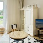 Living room with TV, cabinet, and table. Entrance to terrace with view of garden.