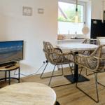 Dining room with round table, chairs, and TV. Wooden floor and window with blinds.