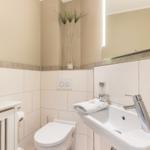 Badezimmer mit Toilette, Waschbecken und Spiegel. Dekorative Pflanzen und Handtuch.