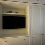 Ein eingebautes TV-Fach mit Schublade und dekorativen Gegenständen.