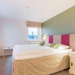 Schlafzimmer mit Bett, Nachttisch und Fenster zum Leuchtturm