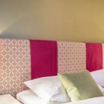 Schlafzimmer mit Bett, Kopfteil und Wandlampen.