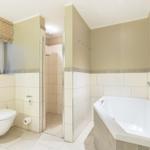 Bad mit Dusche, Badewanne und Toilette. Fenster mit Rollladen.