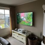 Wohnzimmer mit Fernseher, Kamin und Blick auf den Garten.