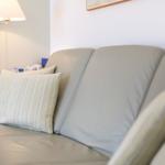 Ein grauer Ledersofa mit Kissen und einer Wandlampe im Hintergrund.