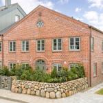 Red brick building with stone wall and green garden border.