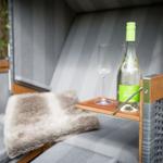 Outdoor lounge with bottle and glasses on a table.