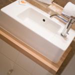 Sink with faucet on wooden top and white cabinet.