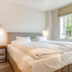 Bedroom with double bed, window, and view of greenery. Adjacent room with heater.