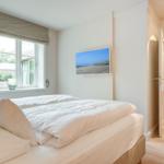 Bedroom with bed, window, and wall picture. Corridor to adjacent rooms.