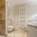 Shower with stone wall, toilet and sink with towels