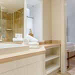Bathroom with shower, sink, and towels. View into the bedroom.