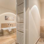 Bath with bathtub, toilet, and heater. Door leads to bedroom.